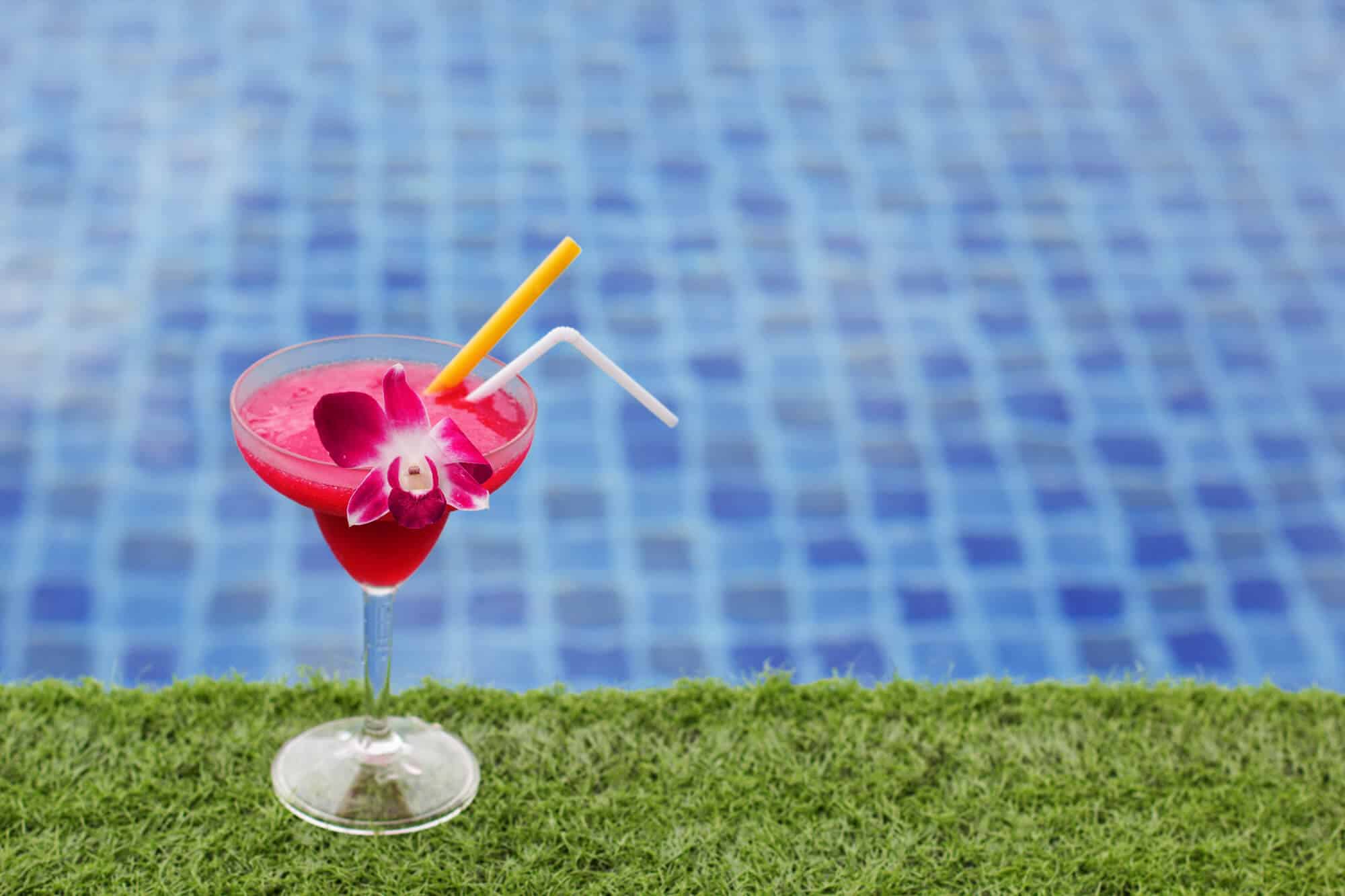 pink frozen drink sitting beside a pool