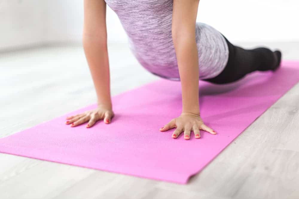 woman practicing yoga on a pink yoga mat