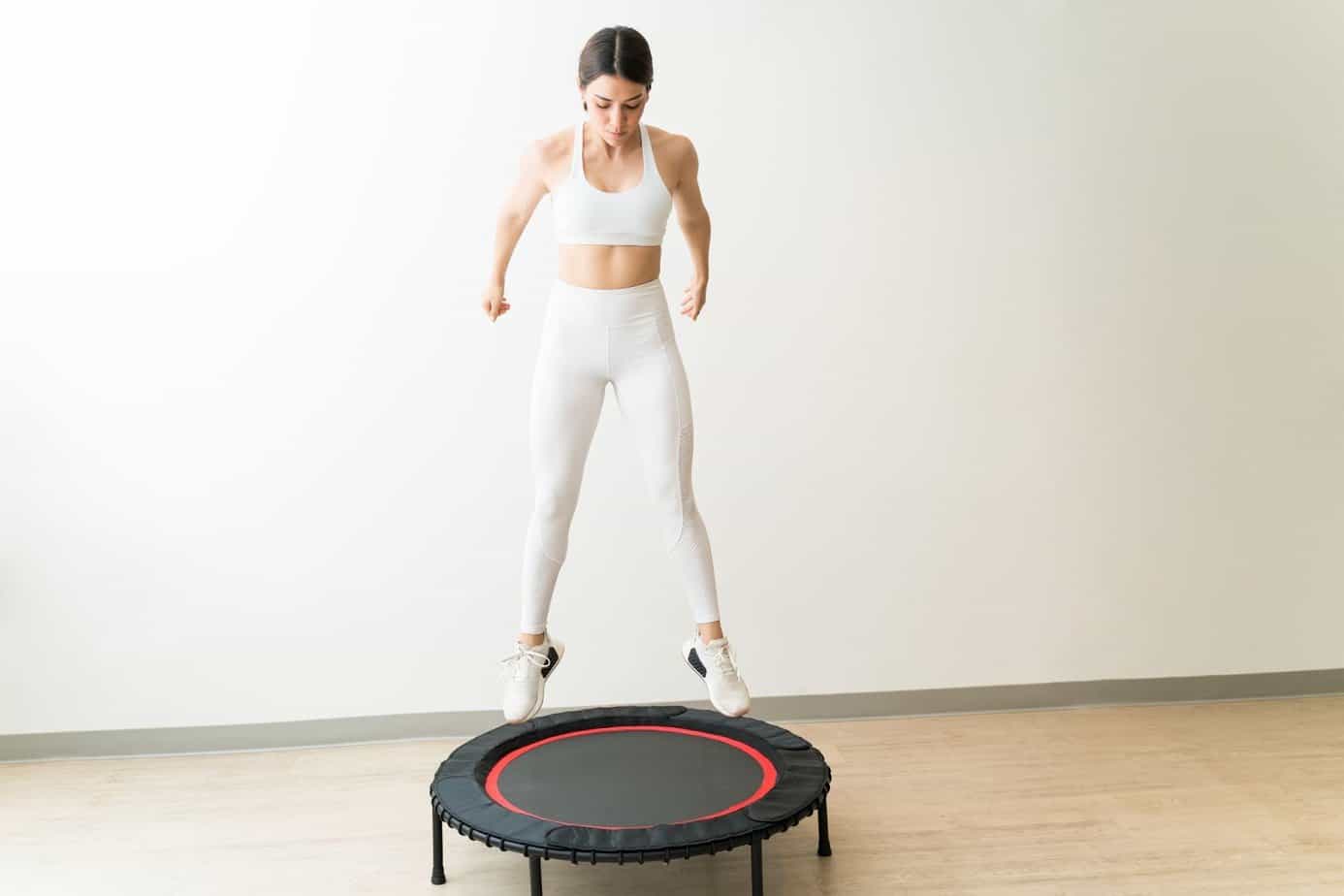 woman in all white jumping on a rebounder trampoline